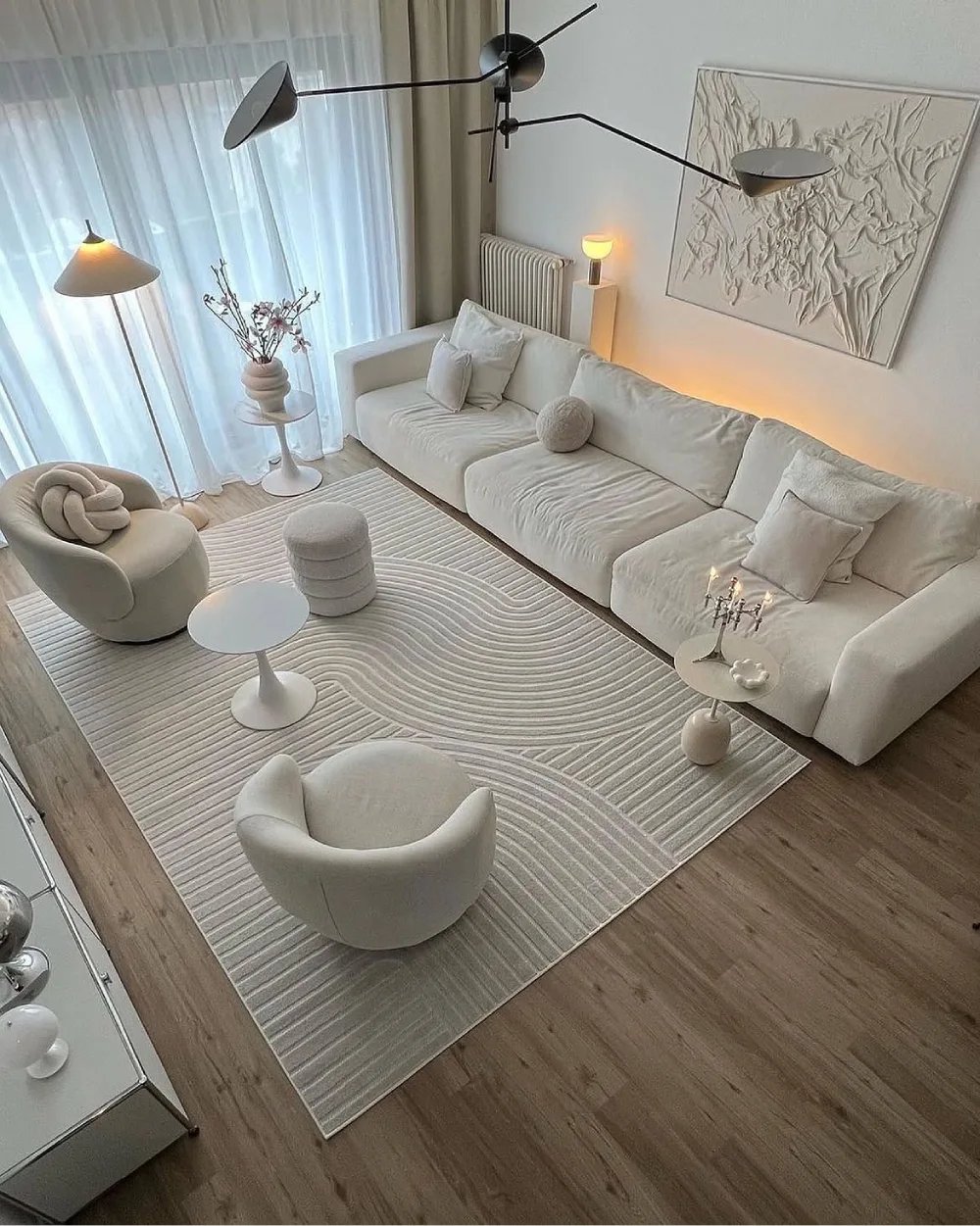 serene white living room with low sectional sofa, sculptural furniture, and textured rug