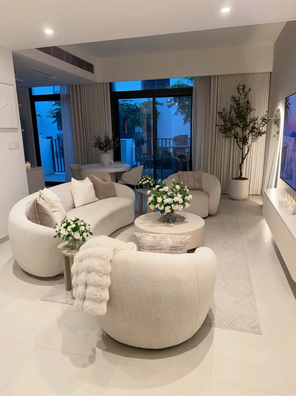 airy contemporary living room with curved cream sofas, round coffee tables, and white decor