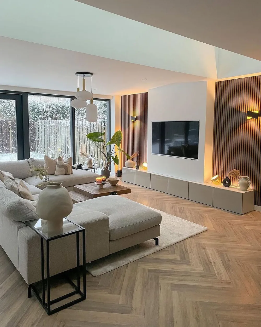 Scandinavian-inspired living room with cream sofas, wood flooring, slatted walls, and warm lighting