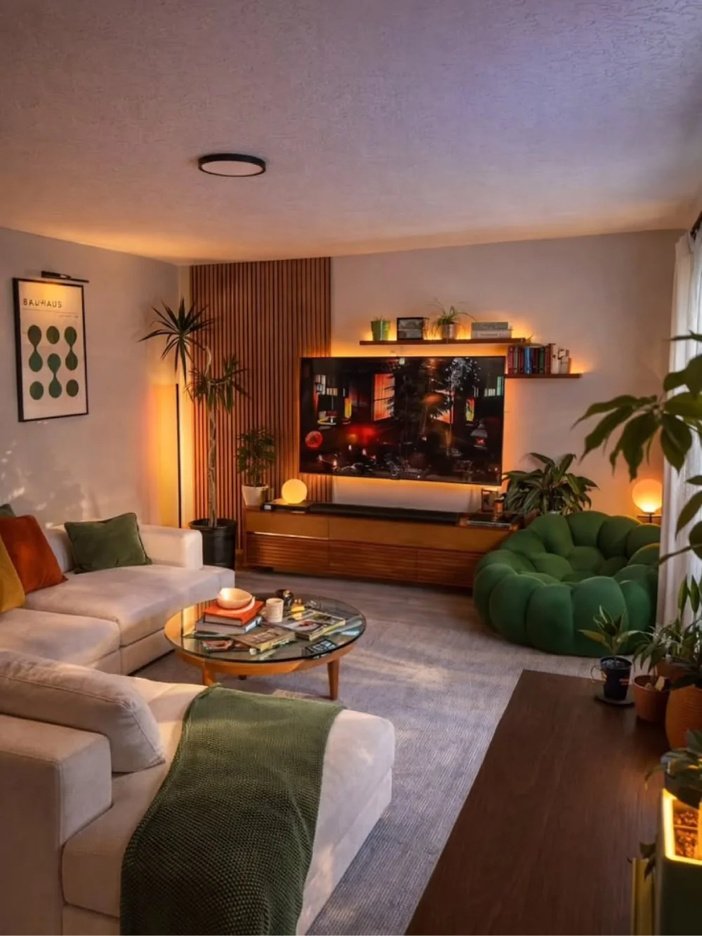 moody living room with deep green accent chair, warm wood furniture, plants, and ambient lighting