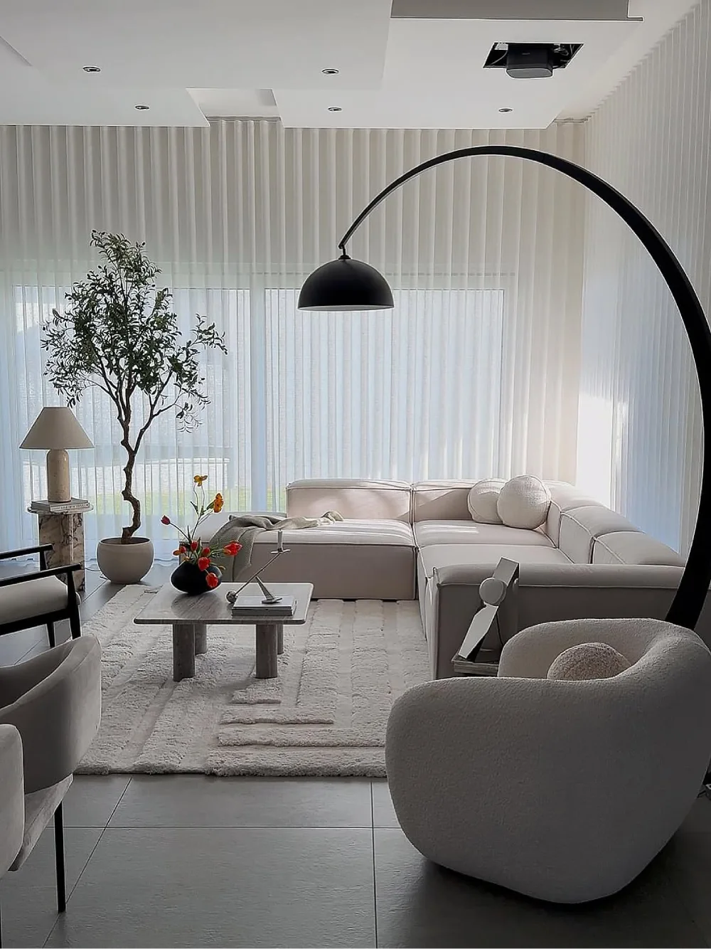 soft white modern living room with curved sectional sofa, sheer curtains, and black arched floor lamp