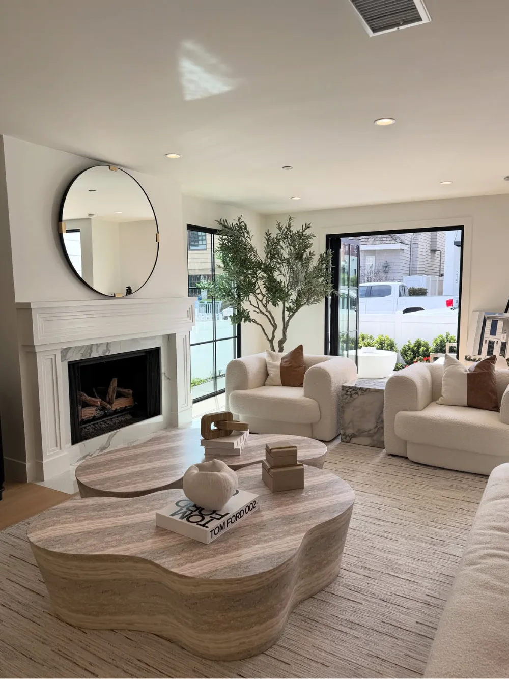 organic modern living room with sculptural wood coffee tables, cream chairs, and fireplace