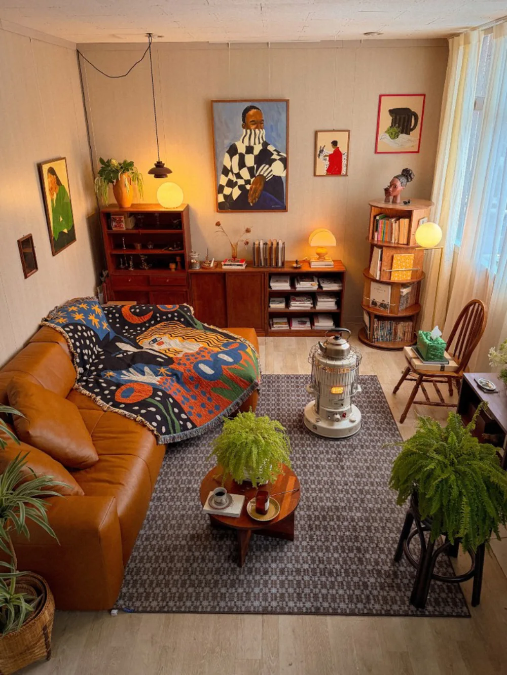 Eclectic living room with leather sofa, colorful throw, vintage furniture, plants, and artwork