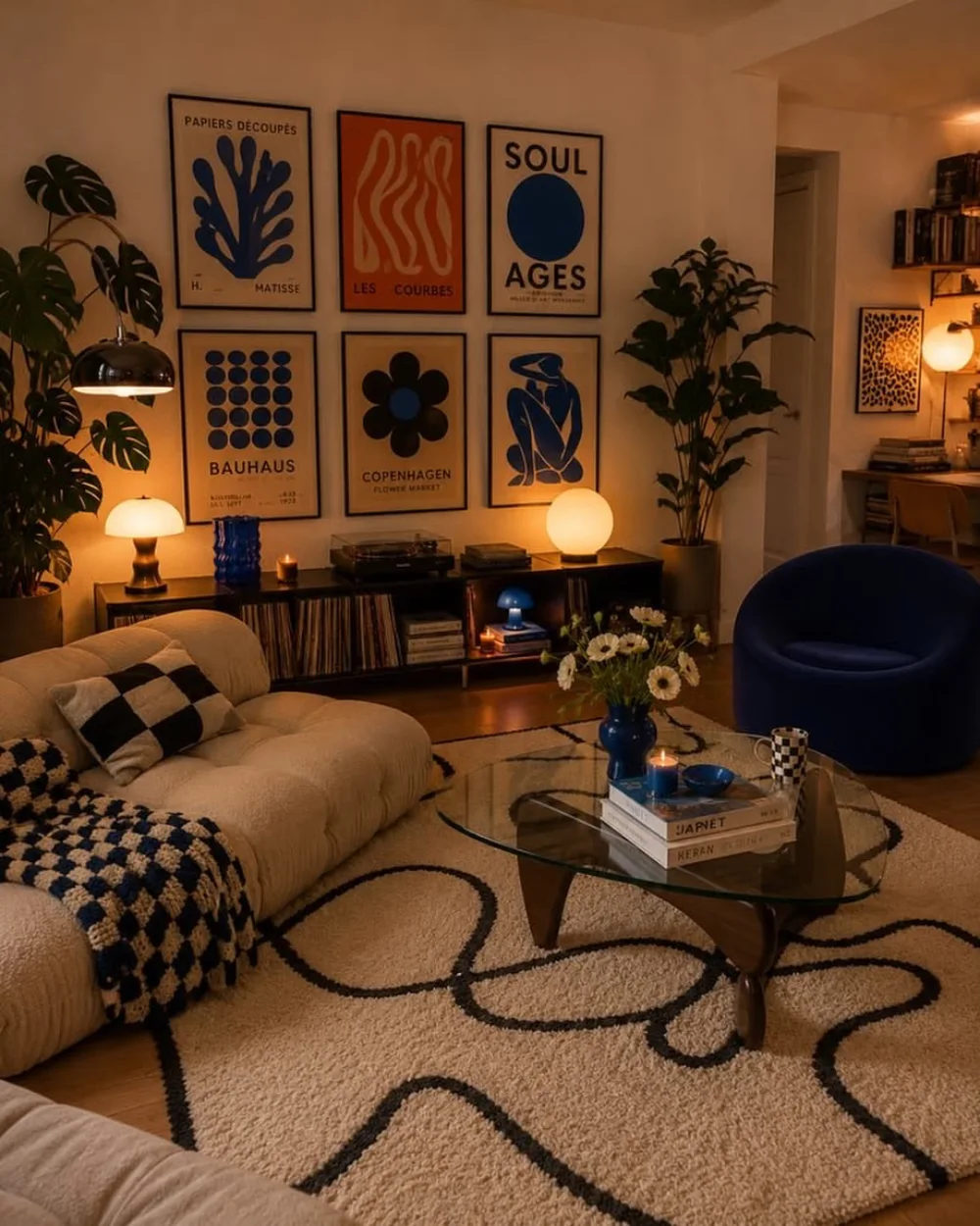 Cozy living room with cream sofa, blue accent chair, bold gallery wall, and soft ambient lighting