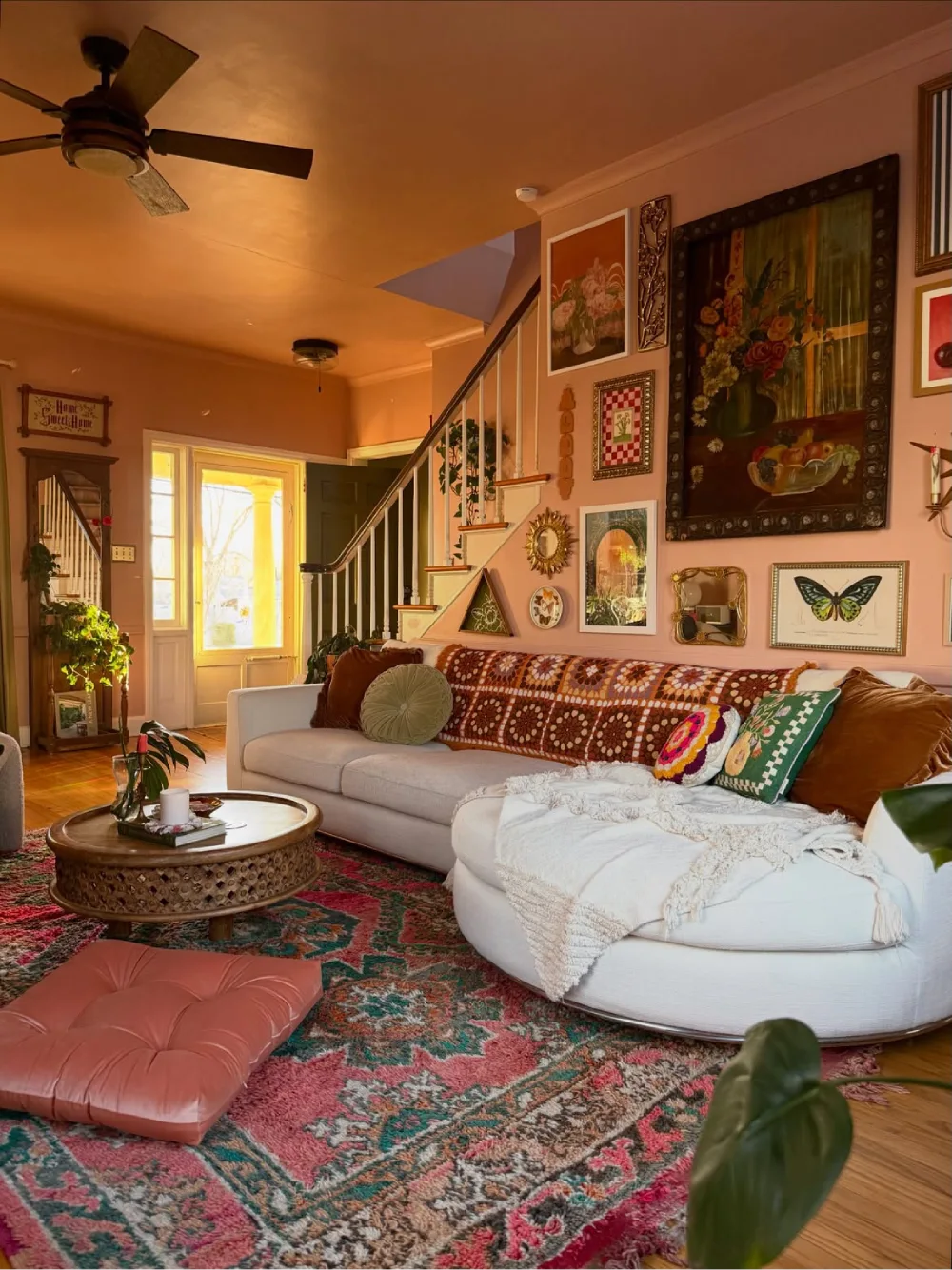 Colorful cozy living room with cream sectional, patterned rug, gallery wall, and layered cushions