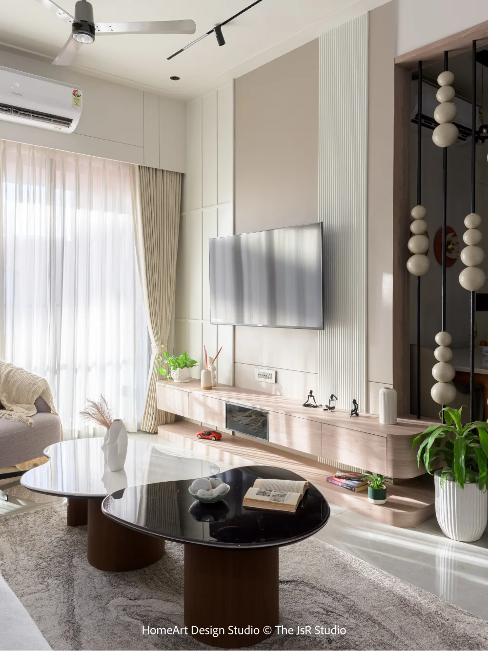 Light-filled modern living room with a minimalist TV wall, wood console, round coffee tables, and sheer curtains