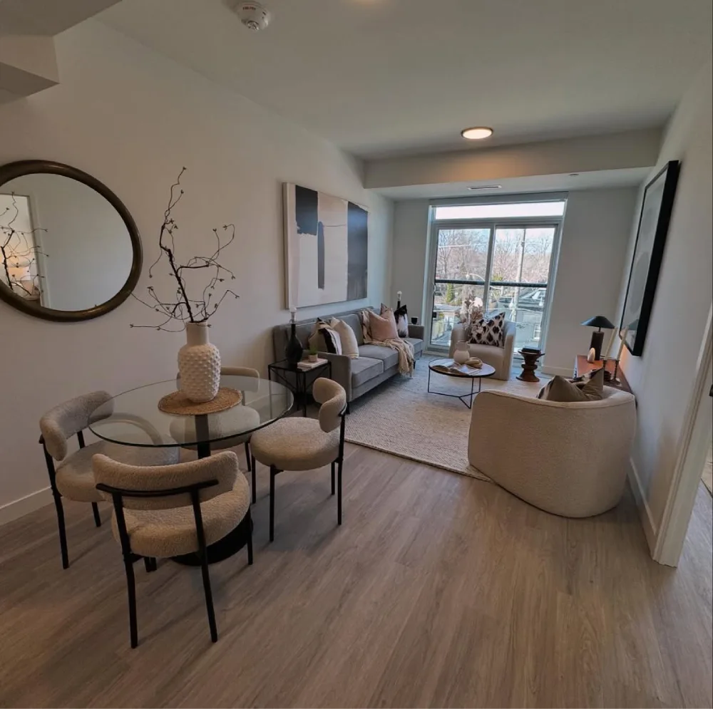 Apartment living and dining room with a round glass table, neutral seating, and defined living area