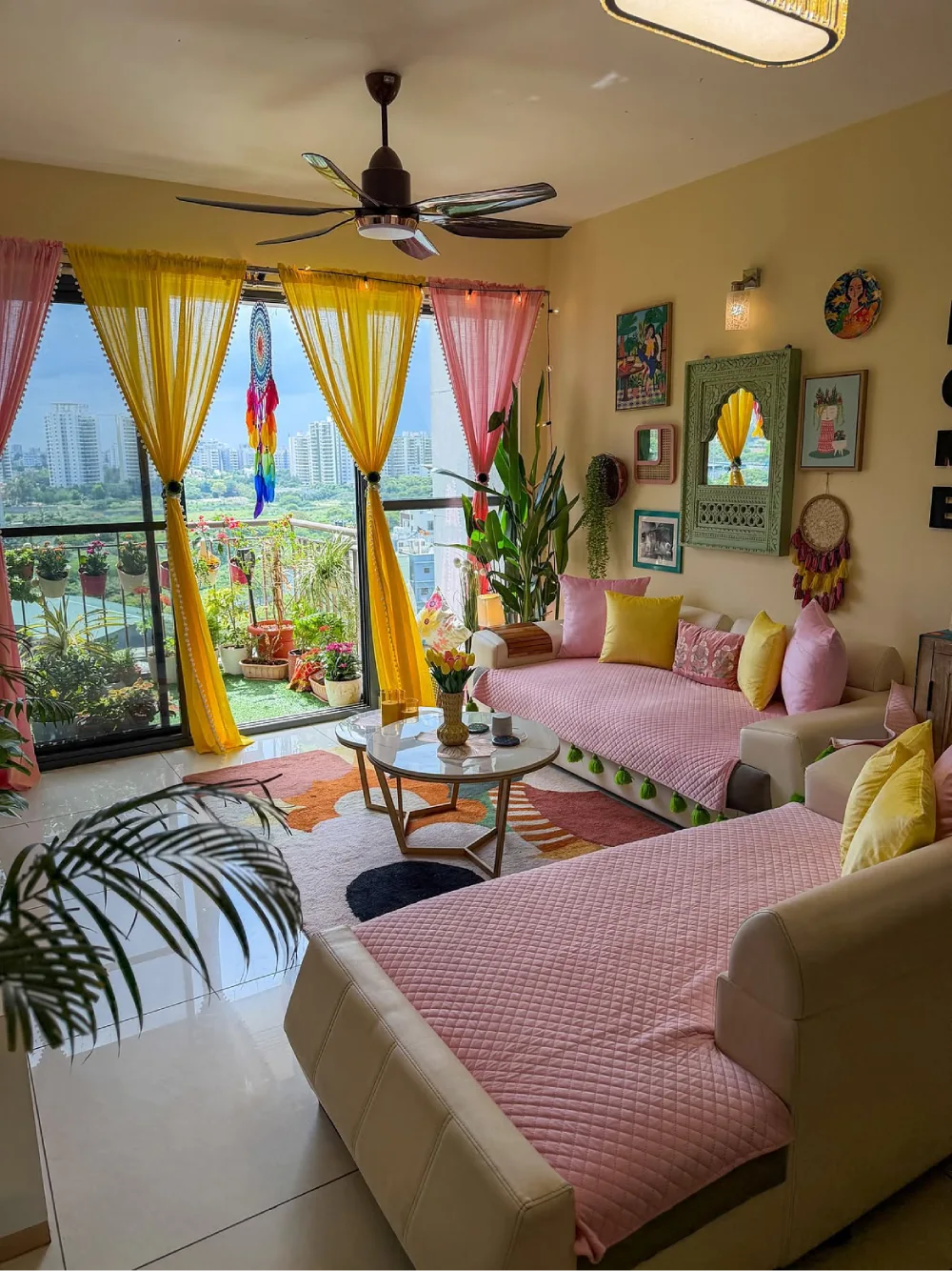 Colorful apartment living room with pink sofas, yellow curtains, plants, and eclectic wall decor