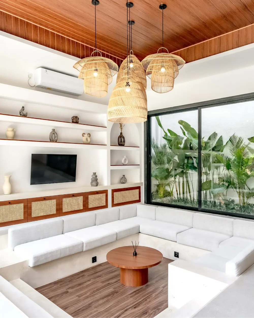 Bright sunken living room with white built-in sectional seating and woven pendant lights