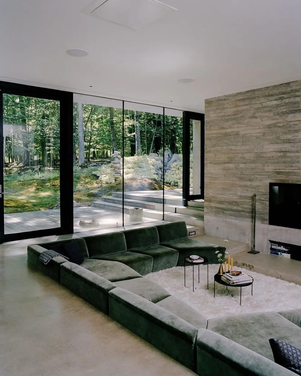 Sunken living room with a green sectional overlooking a forest