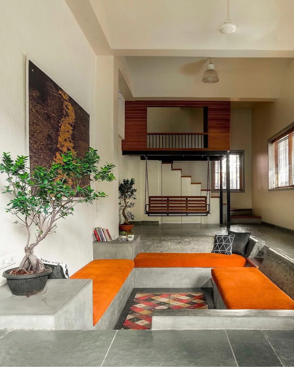 Sunken conversation pit with orange cushions and concrete built-in seating
