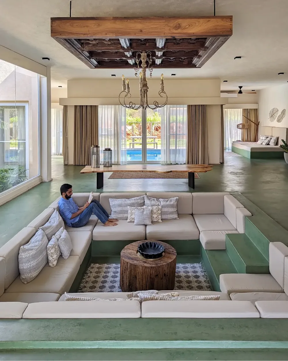 Green sunken conversation pit with cream seating and a wood coffee table