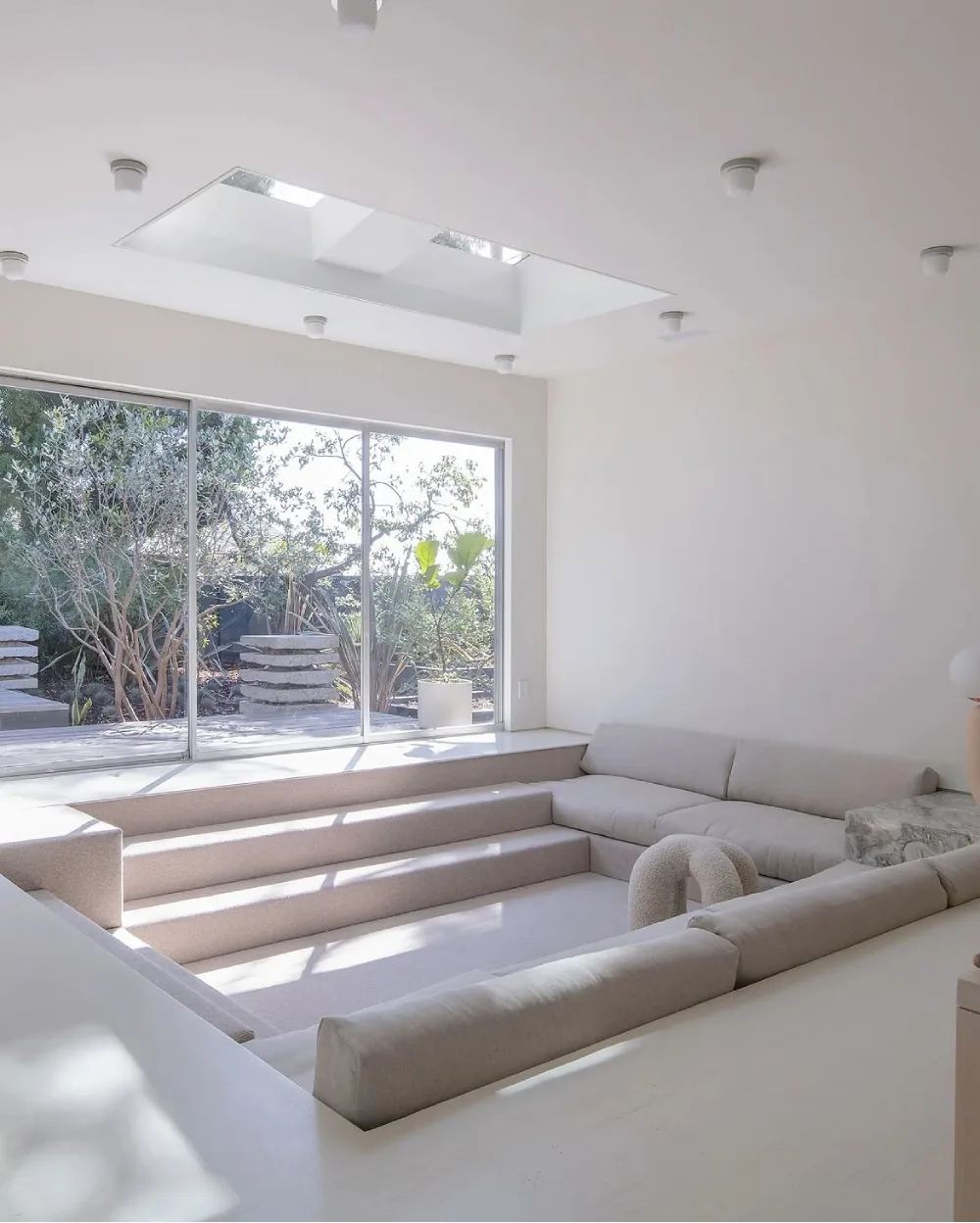 Minimal white sunken conversation pit with skylight and large windows