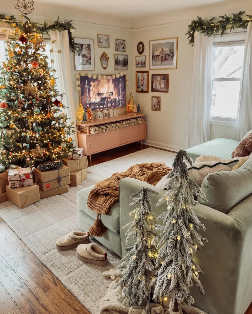 Cozy living room with a frosted Christmas tree, warm blanket, slippers, and softly decorated fireplace wall