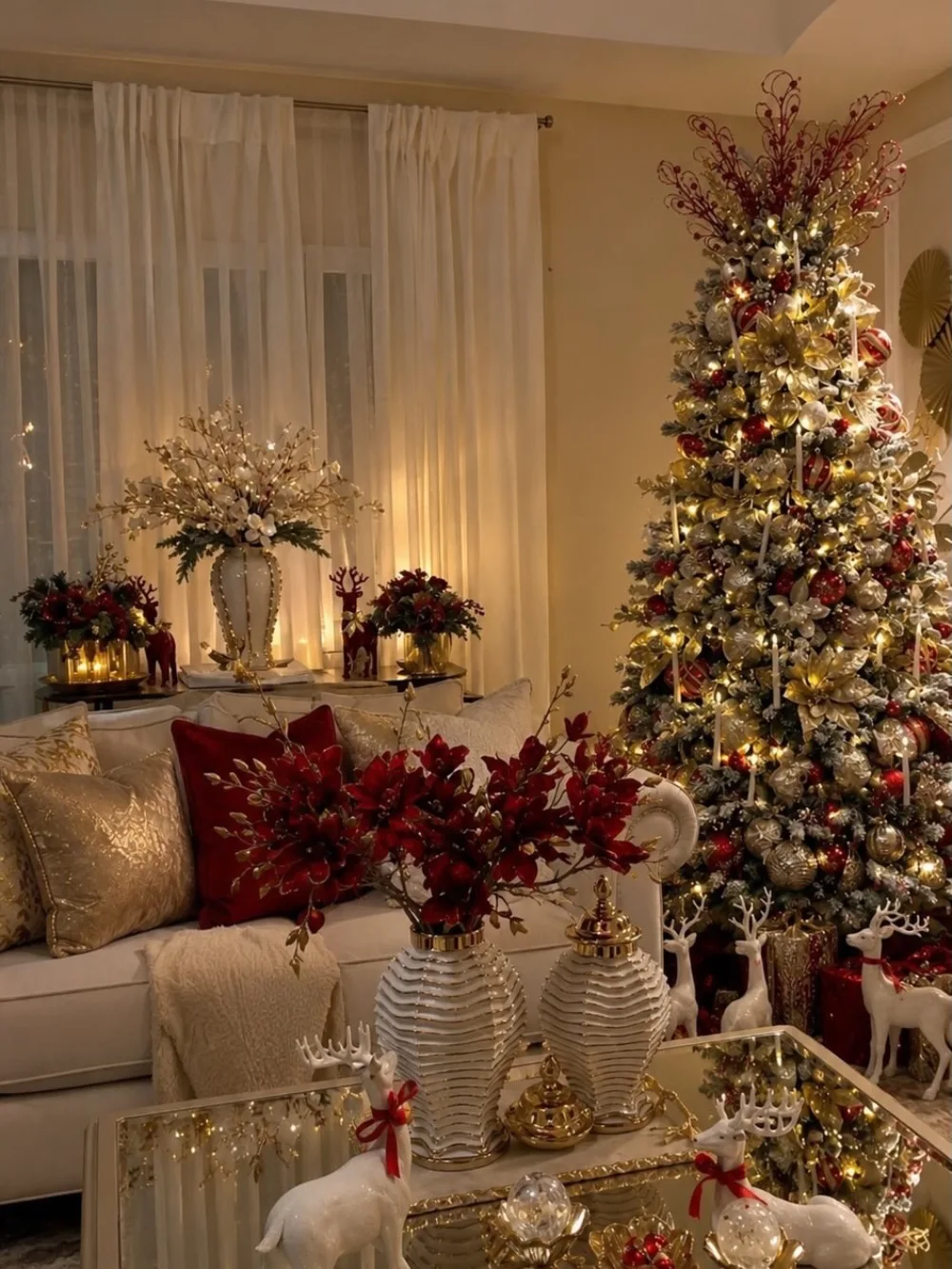 Elegant Christmas living room with red and gold decorations, white sofa, and decorated tree