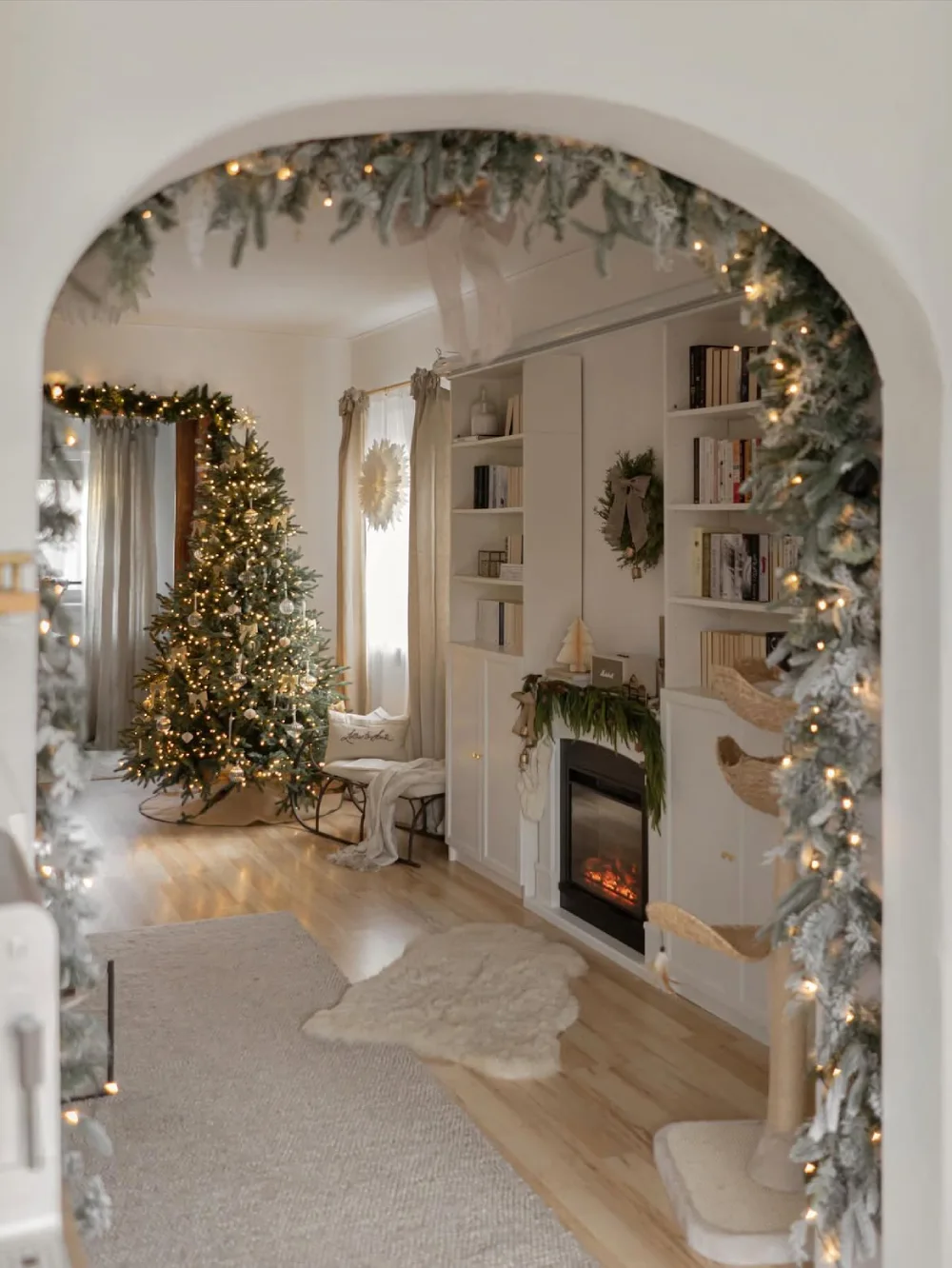 Cozy white living room viewed through an archway decorated with Christmas greenery and warm lights