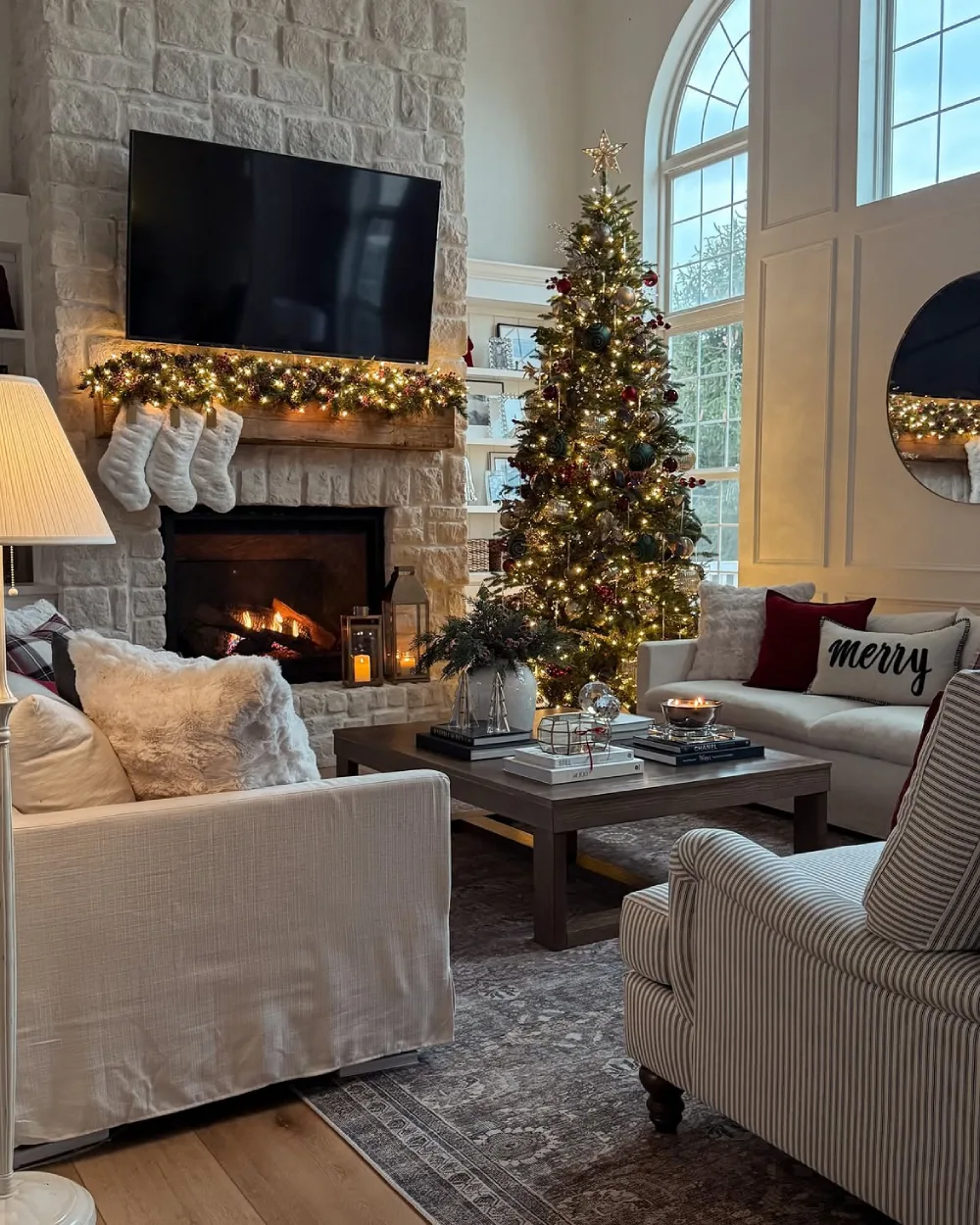 Cozy Christmas living room with a stone fireplace, illuminated garland, decorated tree, and striped armchair