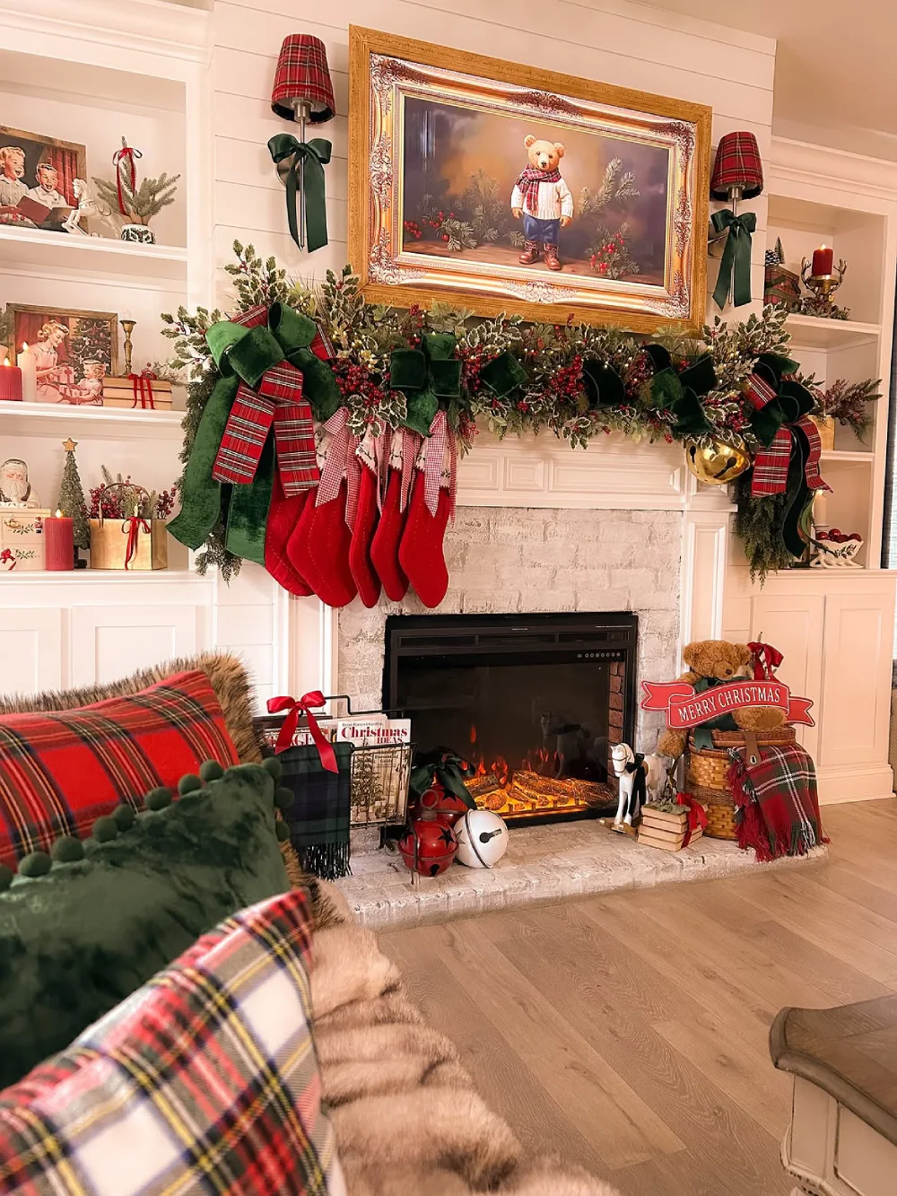 Traditional Christmas fireplace decorated with green garland, red bows, stockings, and plaid accents