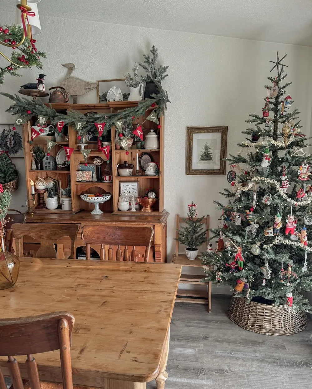 Traditional Christmas living room with a decorated tree, wooden hutch, greenery, and vintage ornaments