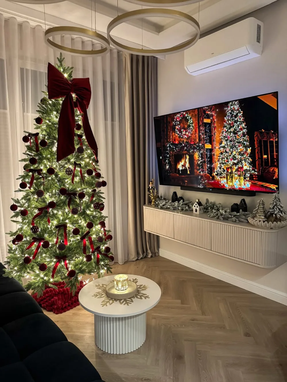 Christmas tree with a large burgundy bow in a modern living room