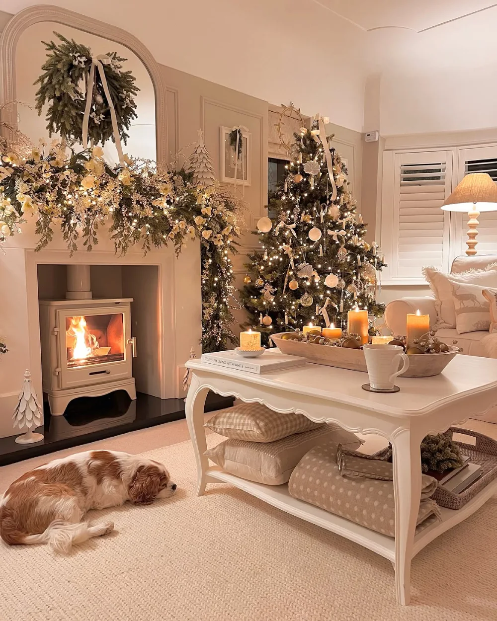 Elegant cream living room with a decorated Christmas tree, fireplace, candles, and floral garland