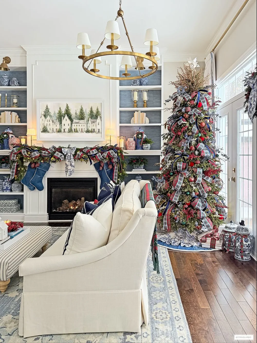 Christmas living room with greenery framing a doorway, red ribbons, and a gold reindeer decoration