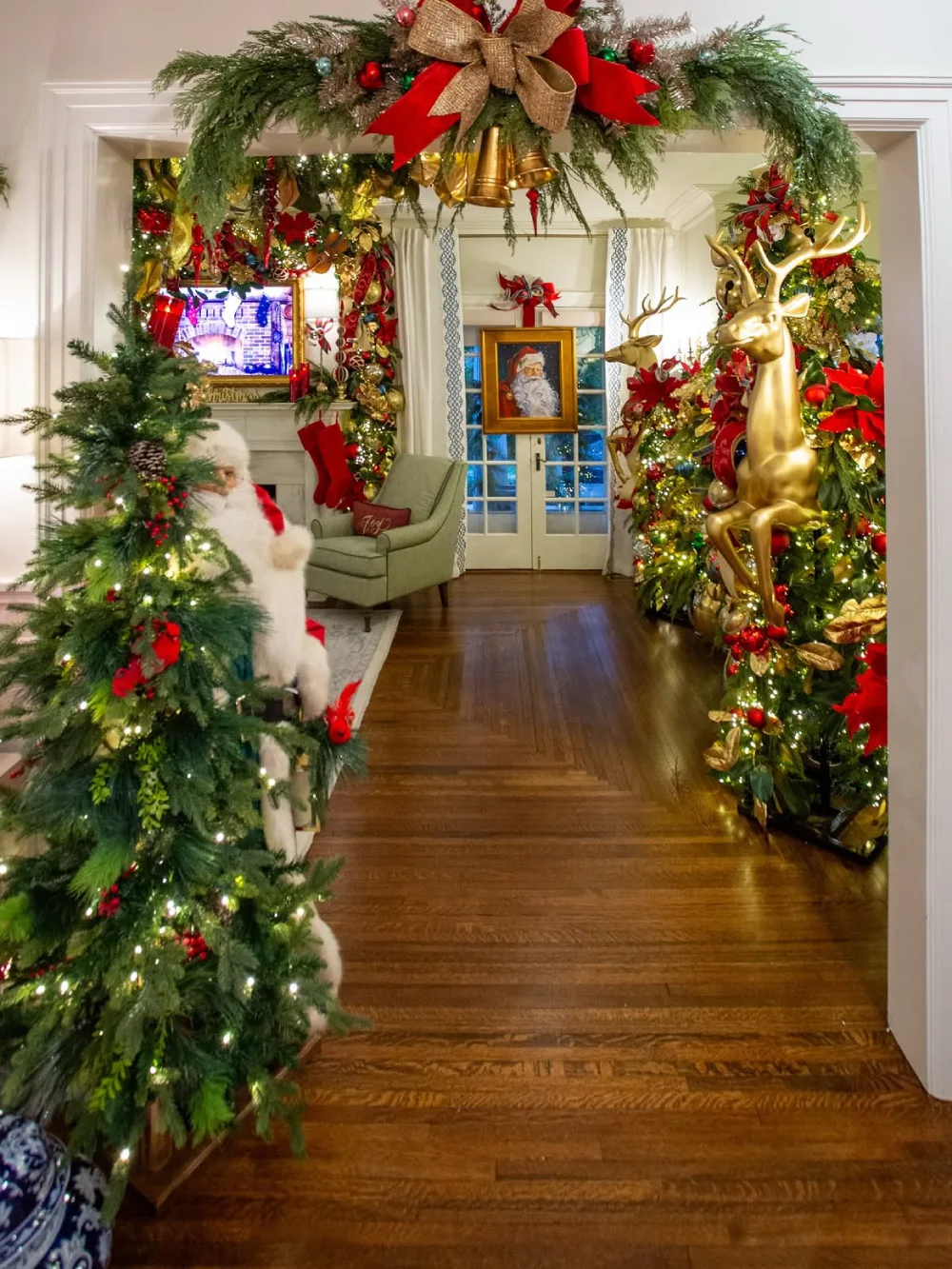 Traditional Christmas living room with red and gold decorations, greenery, and a large gold reindeer