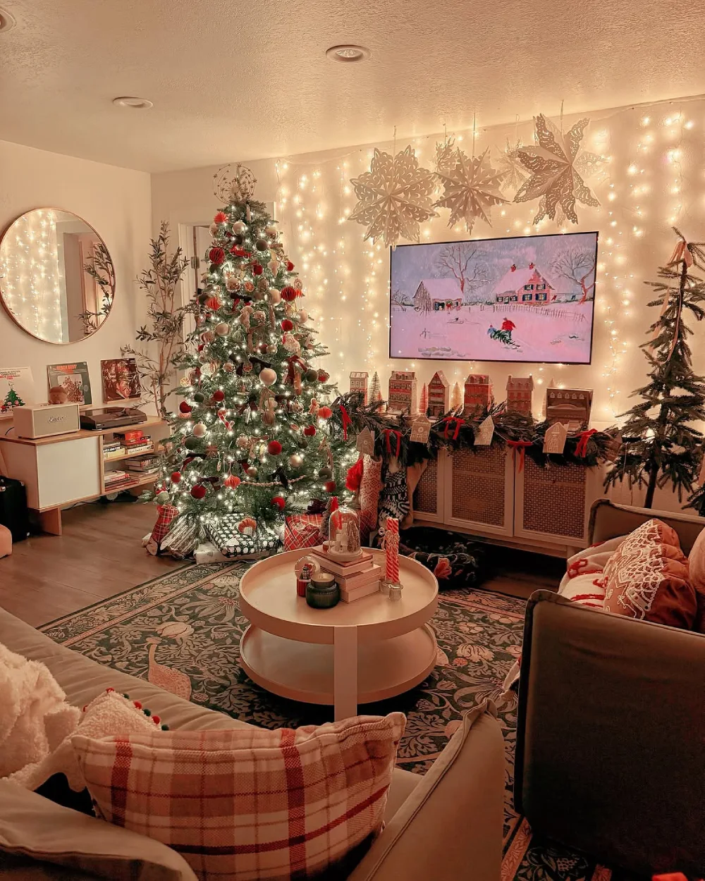 Cozy Christmas living room with a decorated tree, glowing string lights, fireplace display, and winter artwork