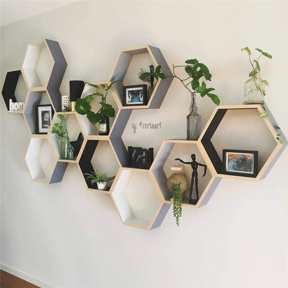 Geometric hexagon floating shelves with white, gray, and natural wood finishes, decorated with small potted plants, framed photos, glass vases, and decorative objects
