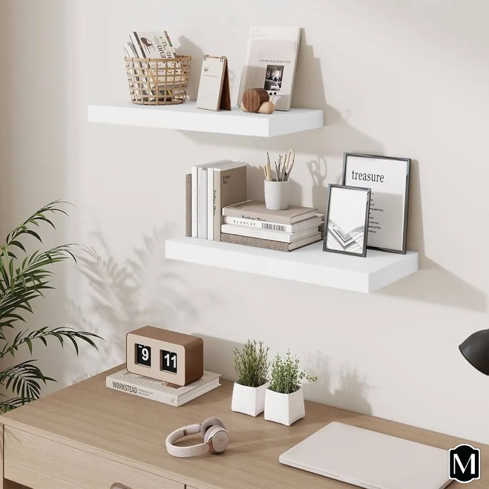 White floating shelves above a wooden desk, styled with neutral books, framed prints, a woven basket, and small decorative accents in a minimalist home office