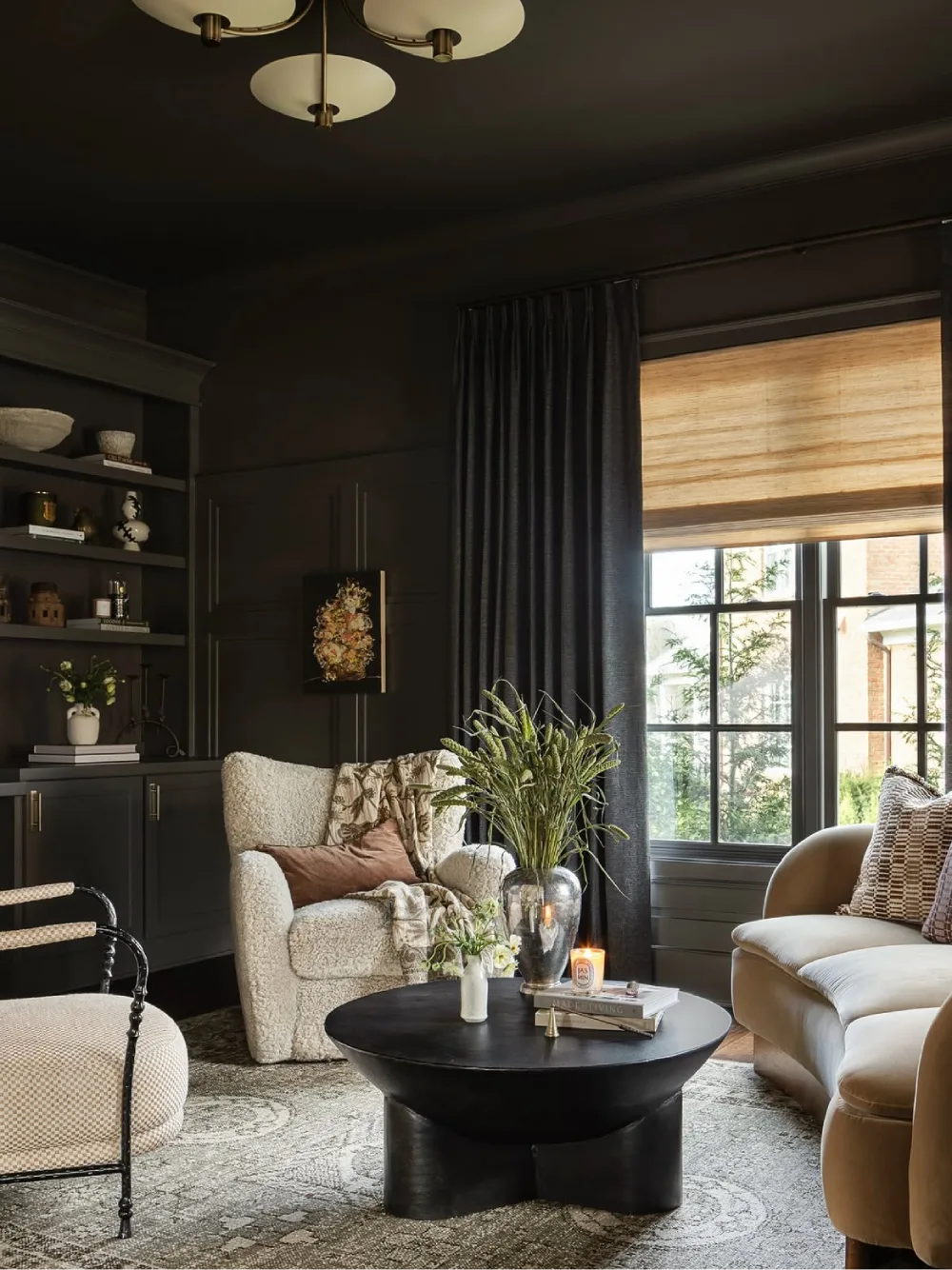 Moody living room with dark charcoal built-in cabinets, cream upholstered furniture, a black coffee table, and warm neutral decor