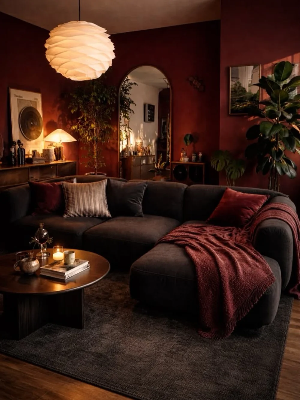Cozy living room with deep burgundy walls, a charcoal sectional sofa, red velvet cushions, and warm lighting