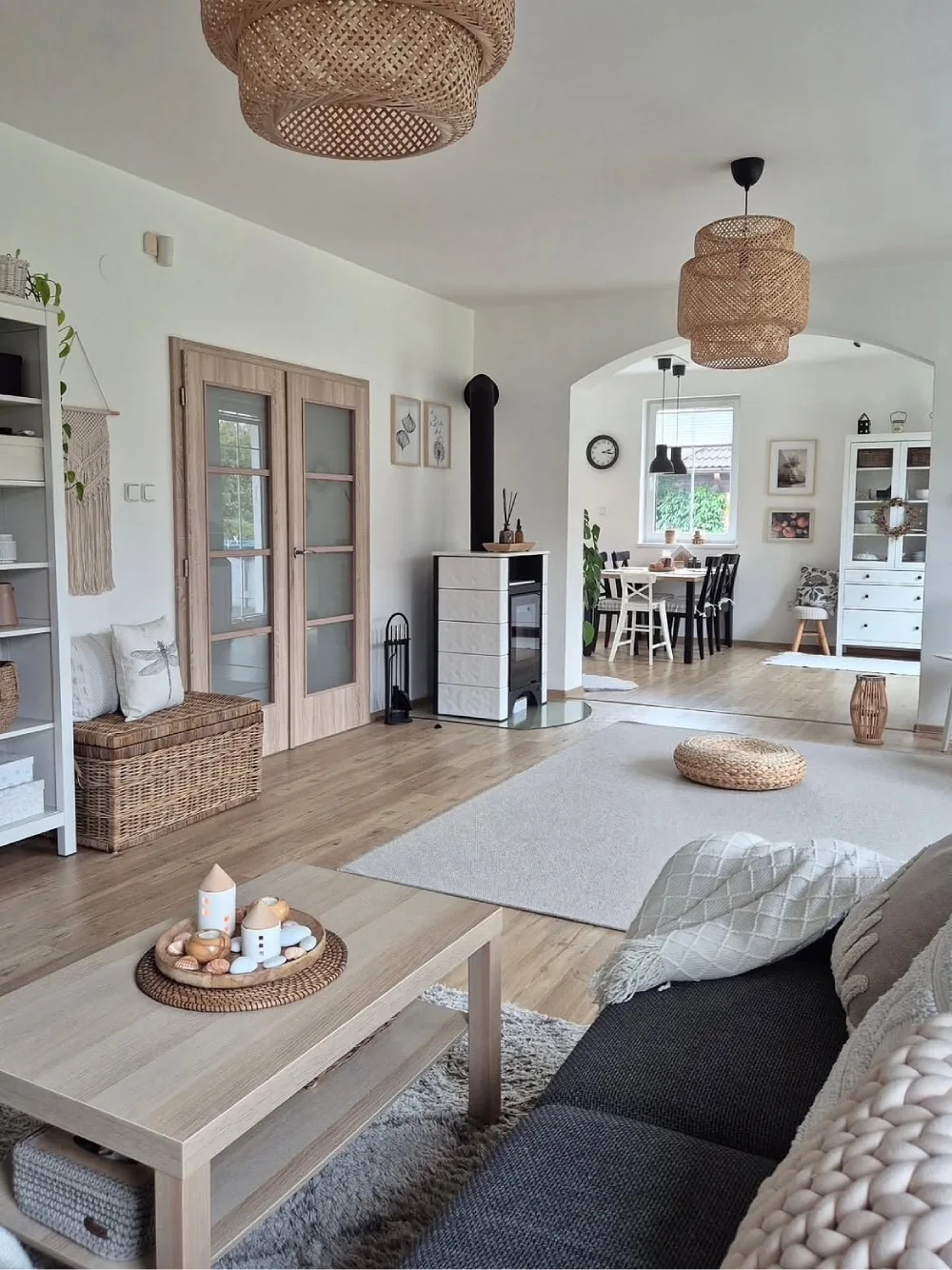 Bright farmhouse living room with woven pendant lights, light wood flooring, a neutral sofa, wicker storage baskets, and natural decor