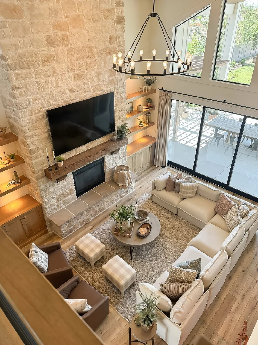 Farmhouse living room with a floor-to-ceiling stone fireplace, mounted television, cream sectional sofa, and large windows