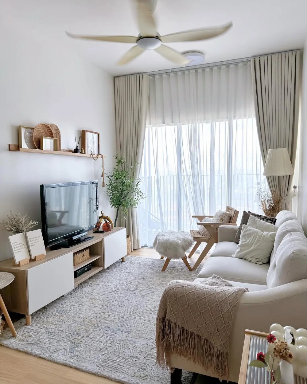 Small living room with a cream sectional, round coffee table, warm lighting, and neutral rug