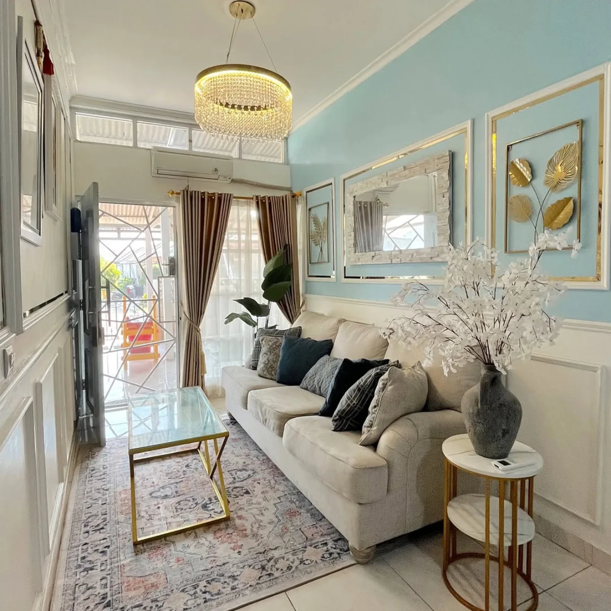 Small living room with a cream sectional, blue walls, gold accents, and a large mirror