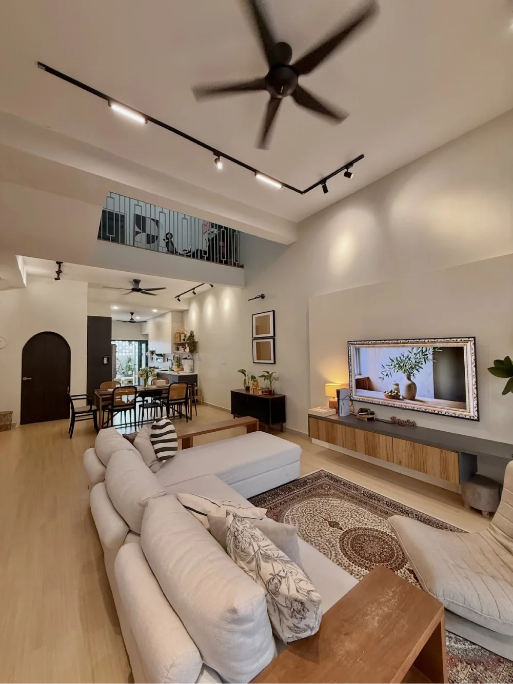 Open-concept living room with cream sectional, dining area, and patterned area rug