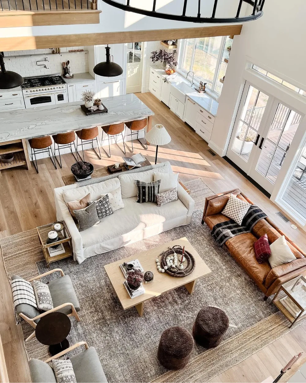 Open-concept kitchen and living room with white and brown sofas surrounding a wood coffee table