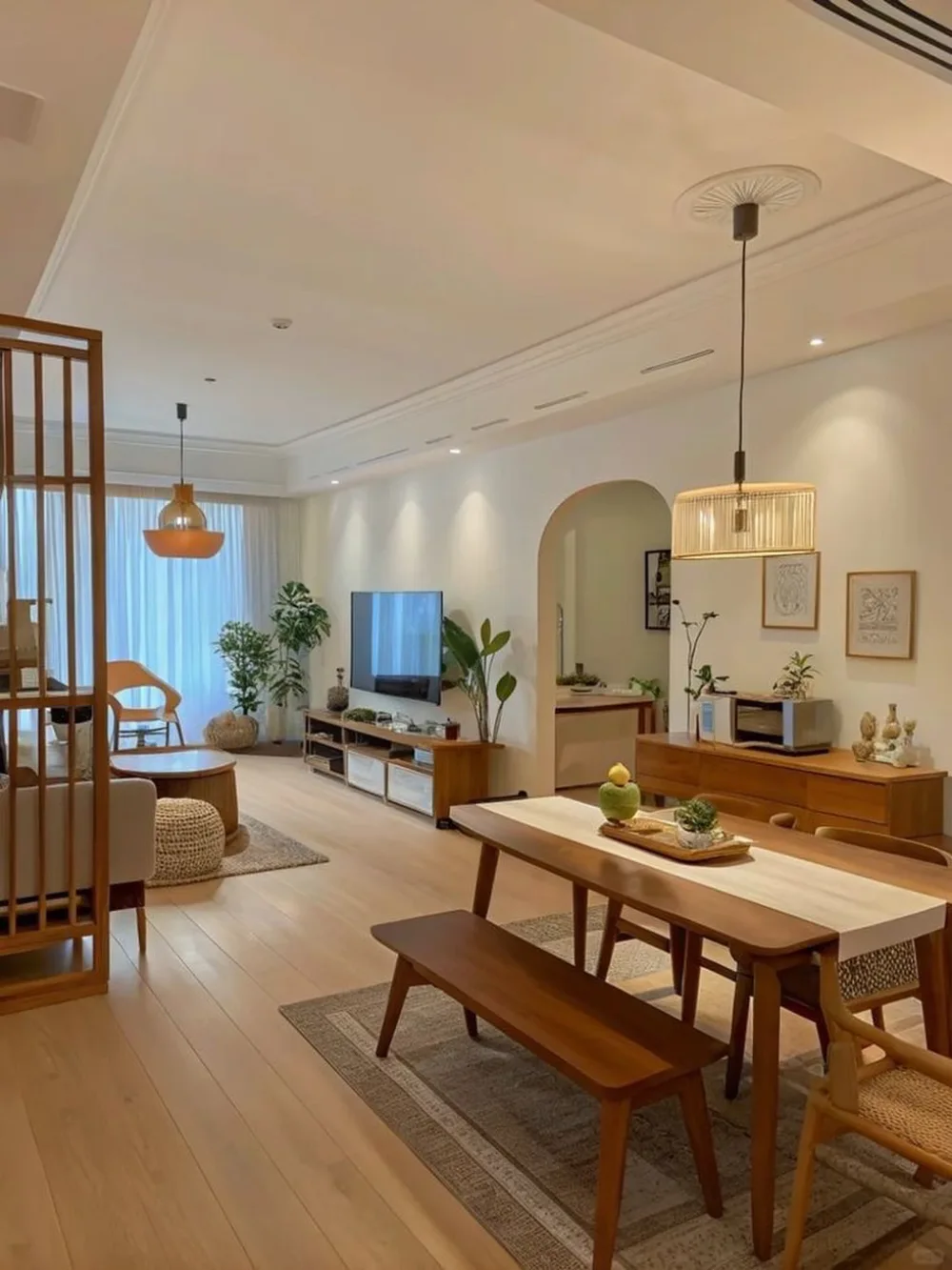 Open dining and living room with wooden table, bench, and warm neutral furniture