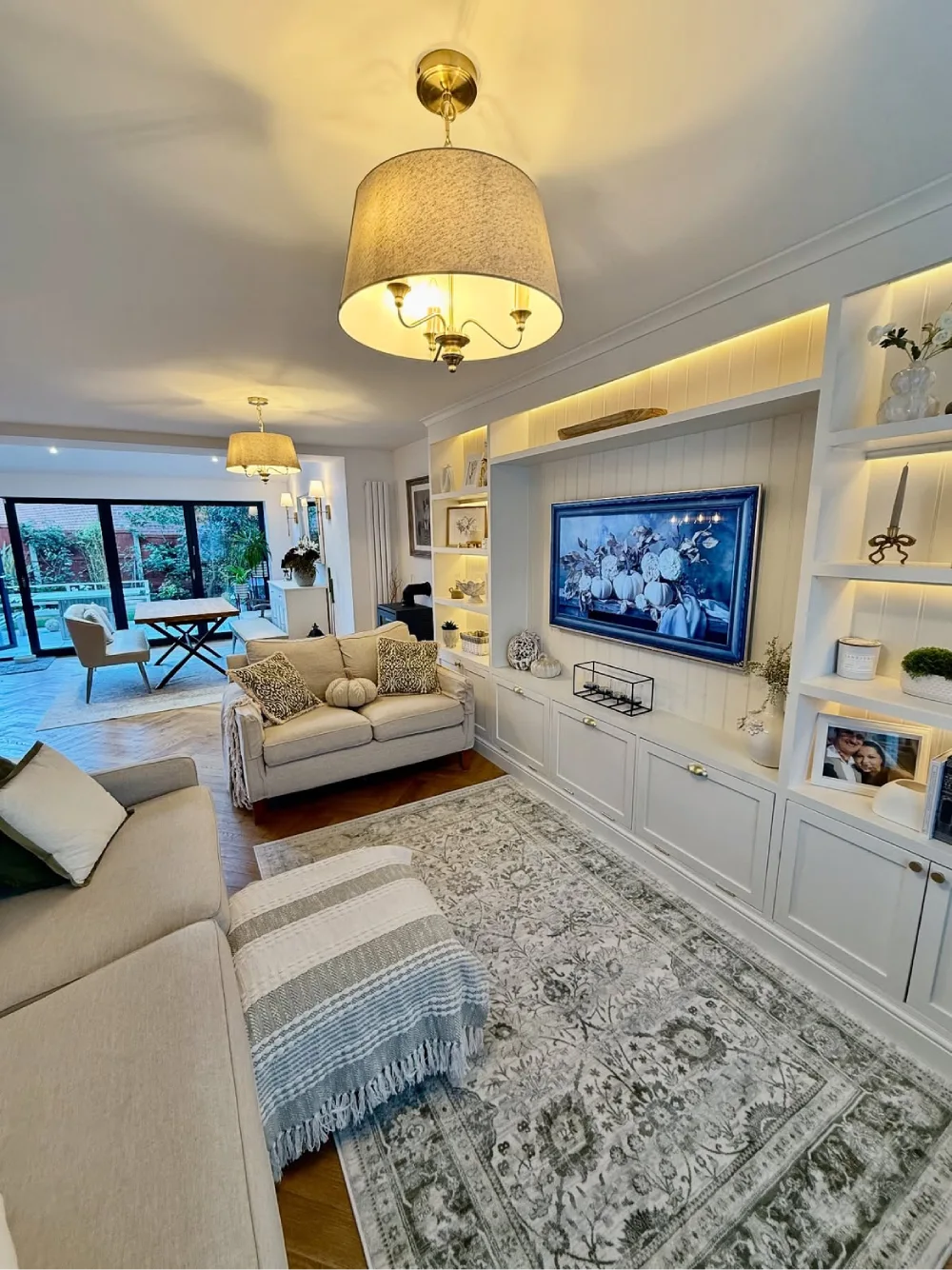 Open-concept living room with cream sofas, built-in TV storage, and dining area beyond