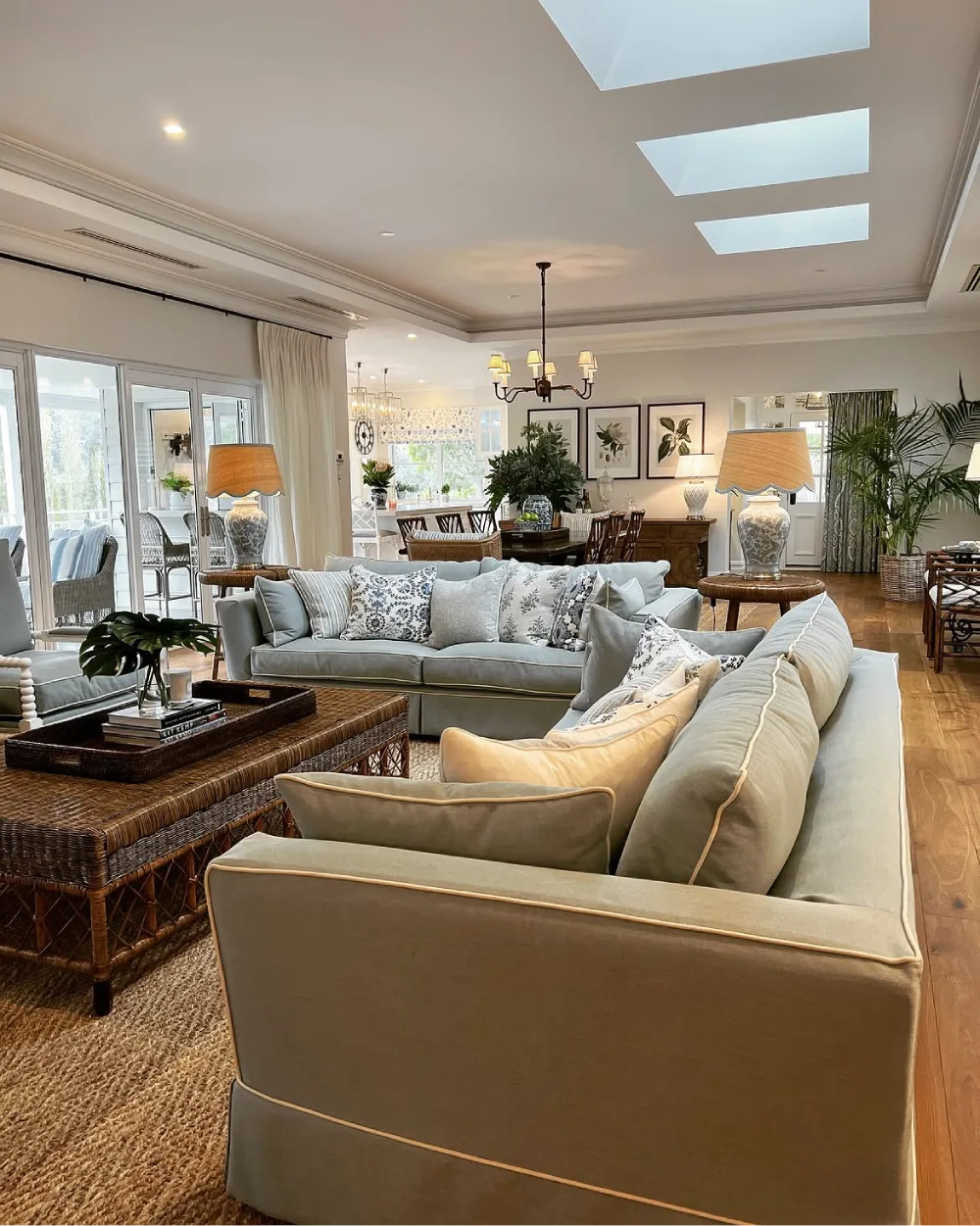 Open-concept living and dining room with pale sofas, patterned rug, and skylights