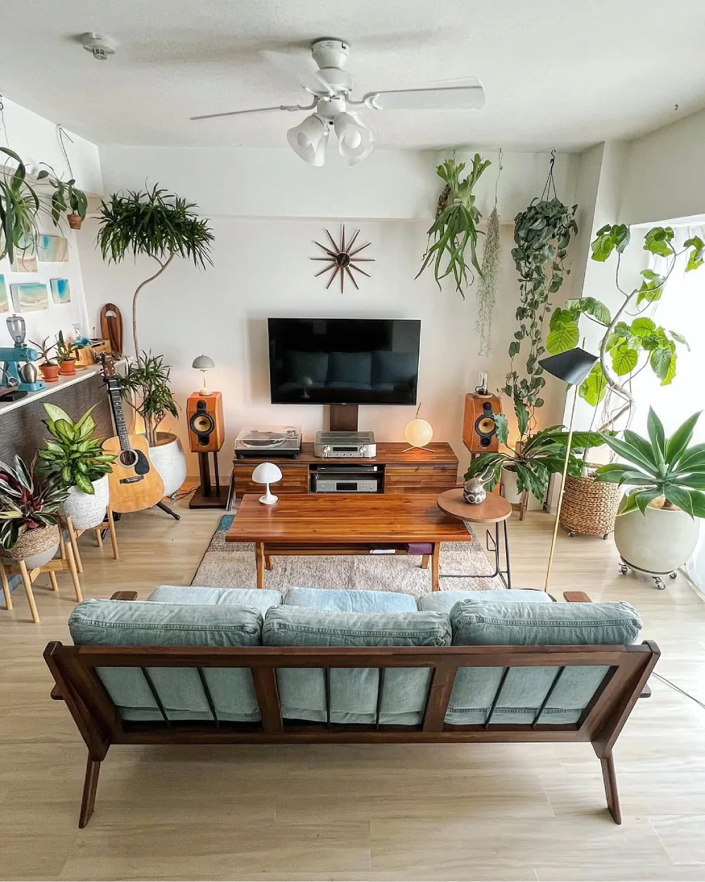 midcentury living room with plants arranged around a TV and wooden console