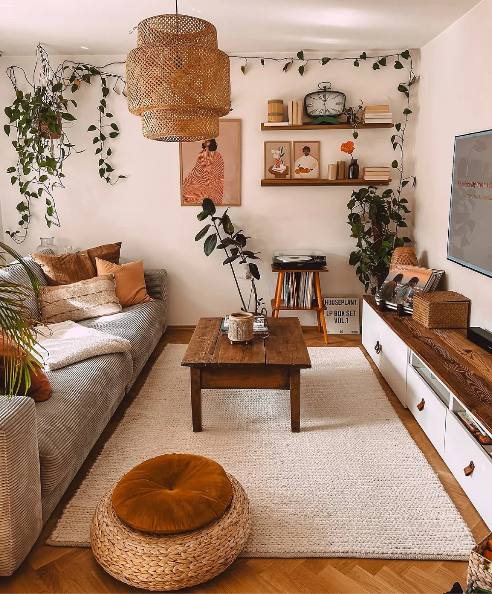 Earthy boho living room with woven pendant light, neutral rug, vintage wood table, and trailing plants