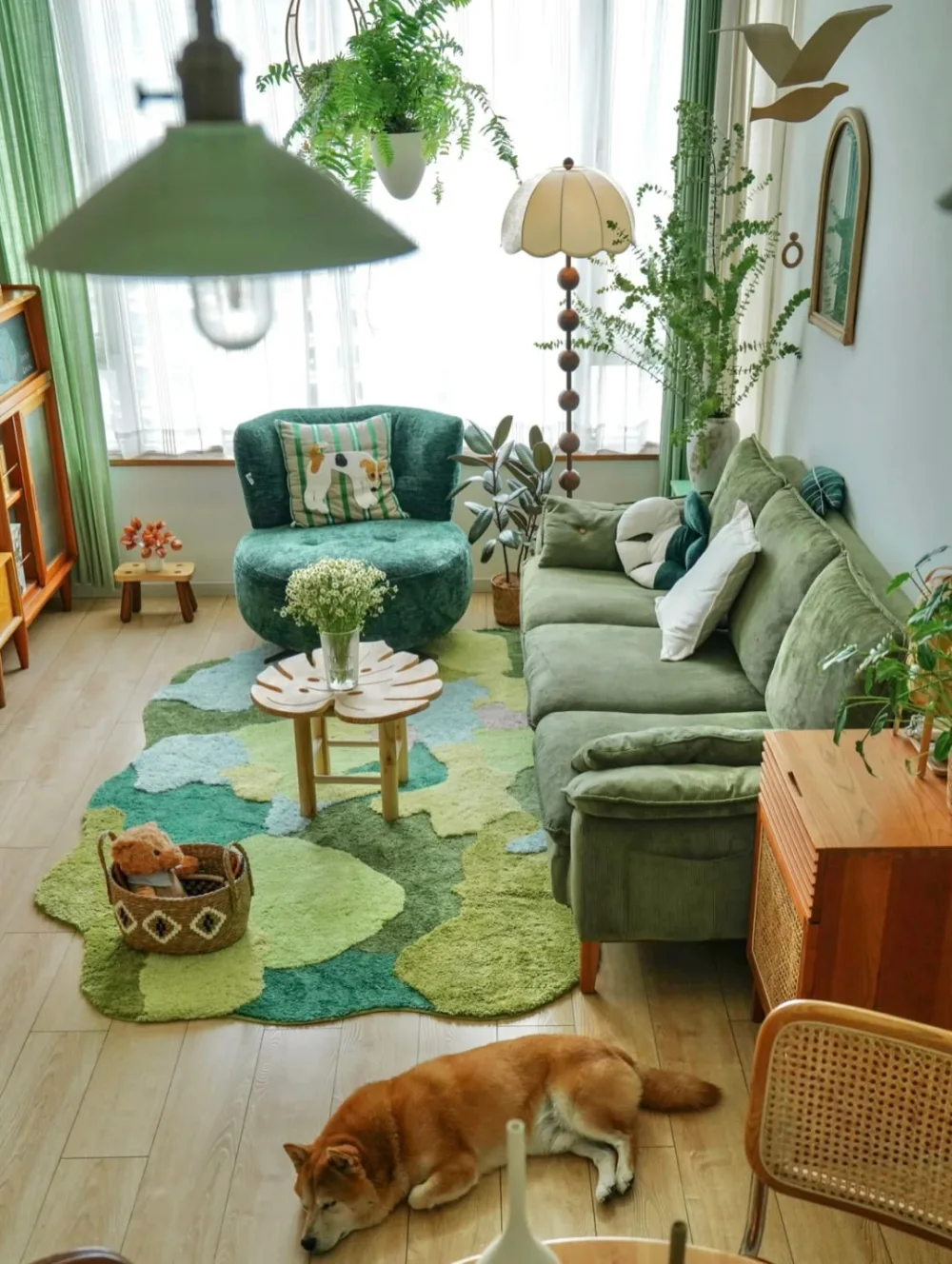 Bright green living room with layered green sofas, leafy plants, natural wood furniture, and botanical rug
