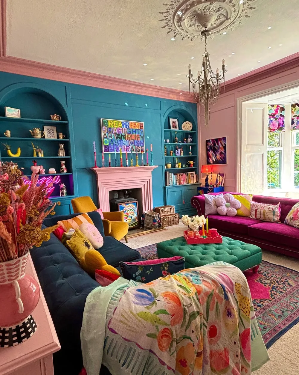 Maximalist living room with teal walls, pink trim, colorful sofas, and patterned textiles