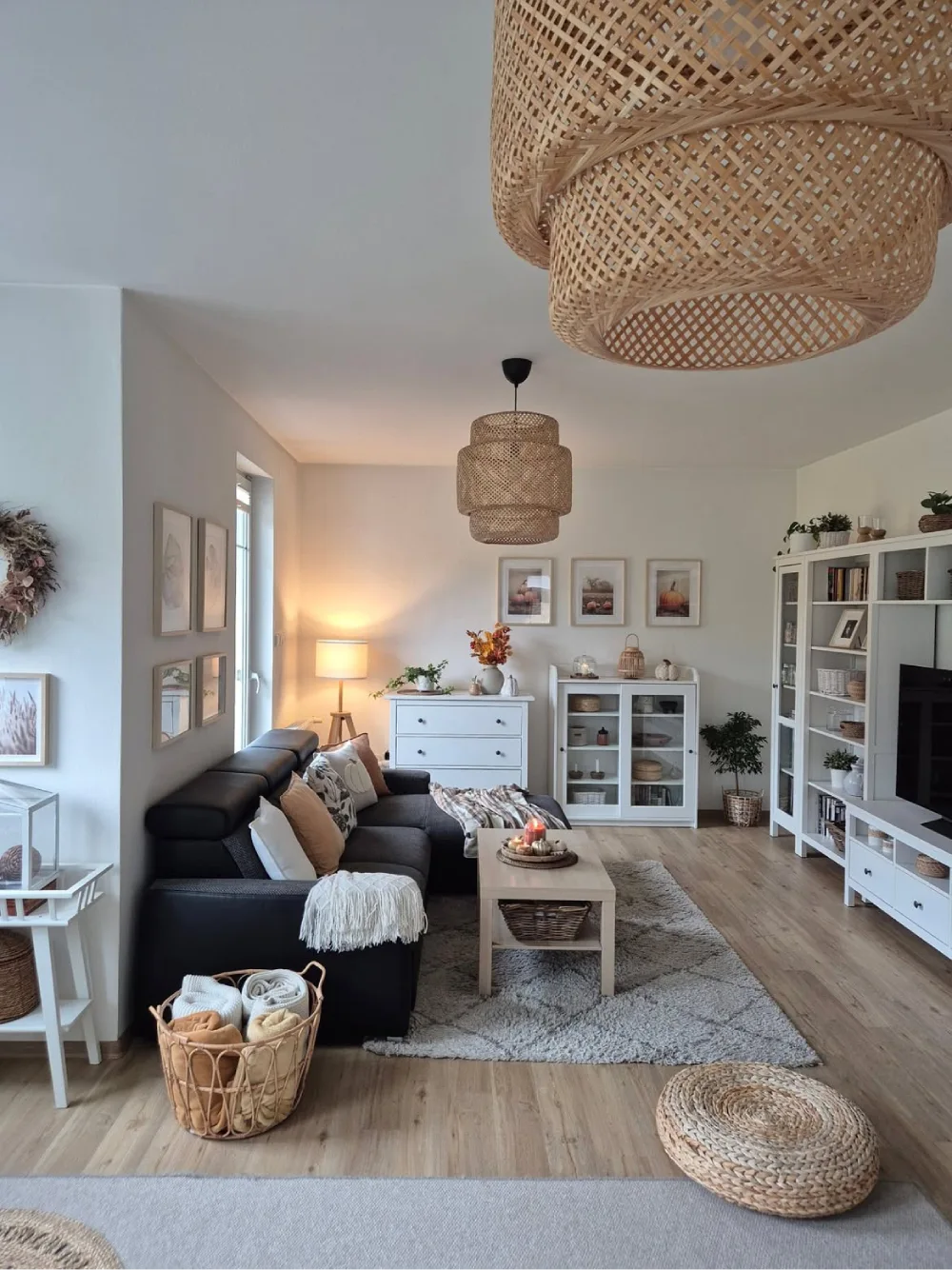 Neutral living room with black sofa, woven pendant lights, baskets, and textured decor