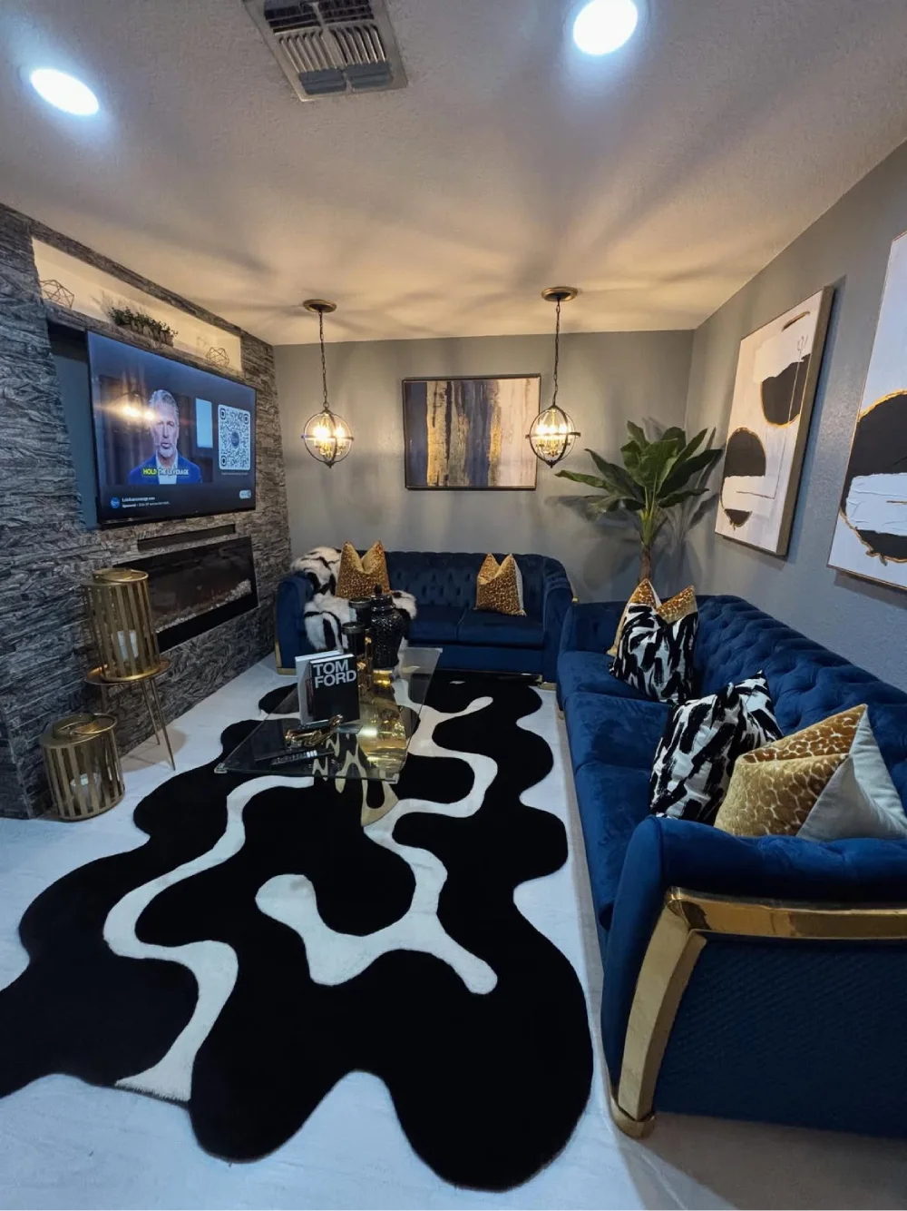 Moody living room with blue sofas, sculptural lighting, plants, and bold abstract artwork