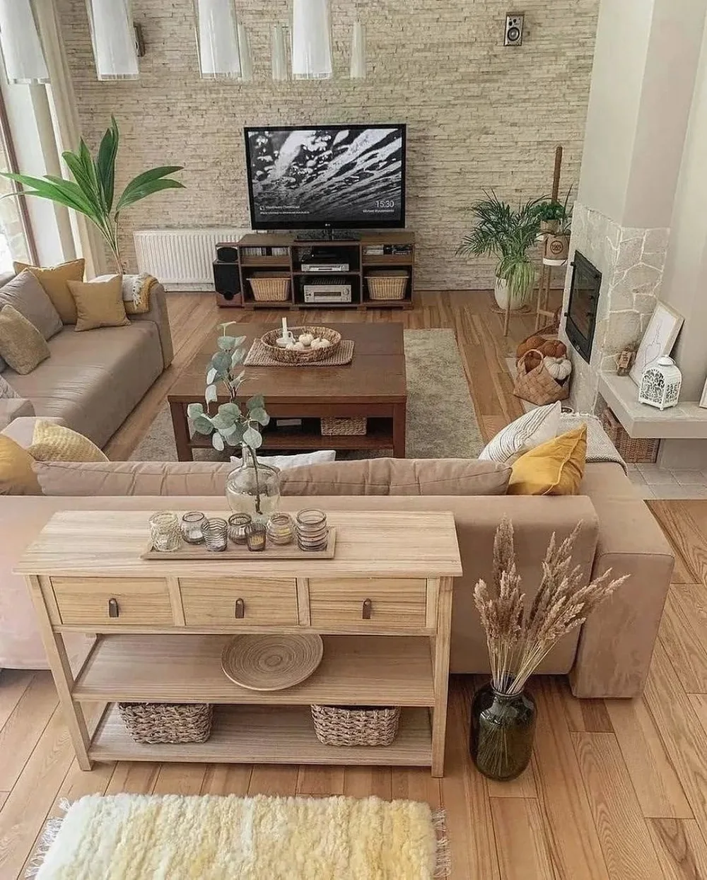 Warm neutral living room with wood furniture, beige sofas, textured rug, and stone accent wall