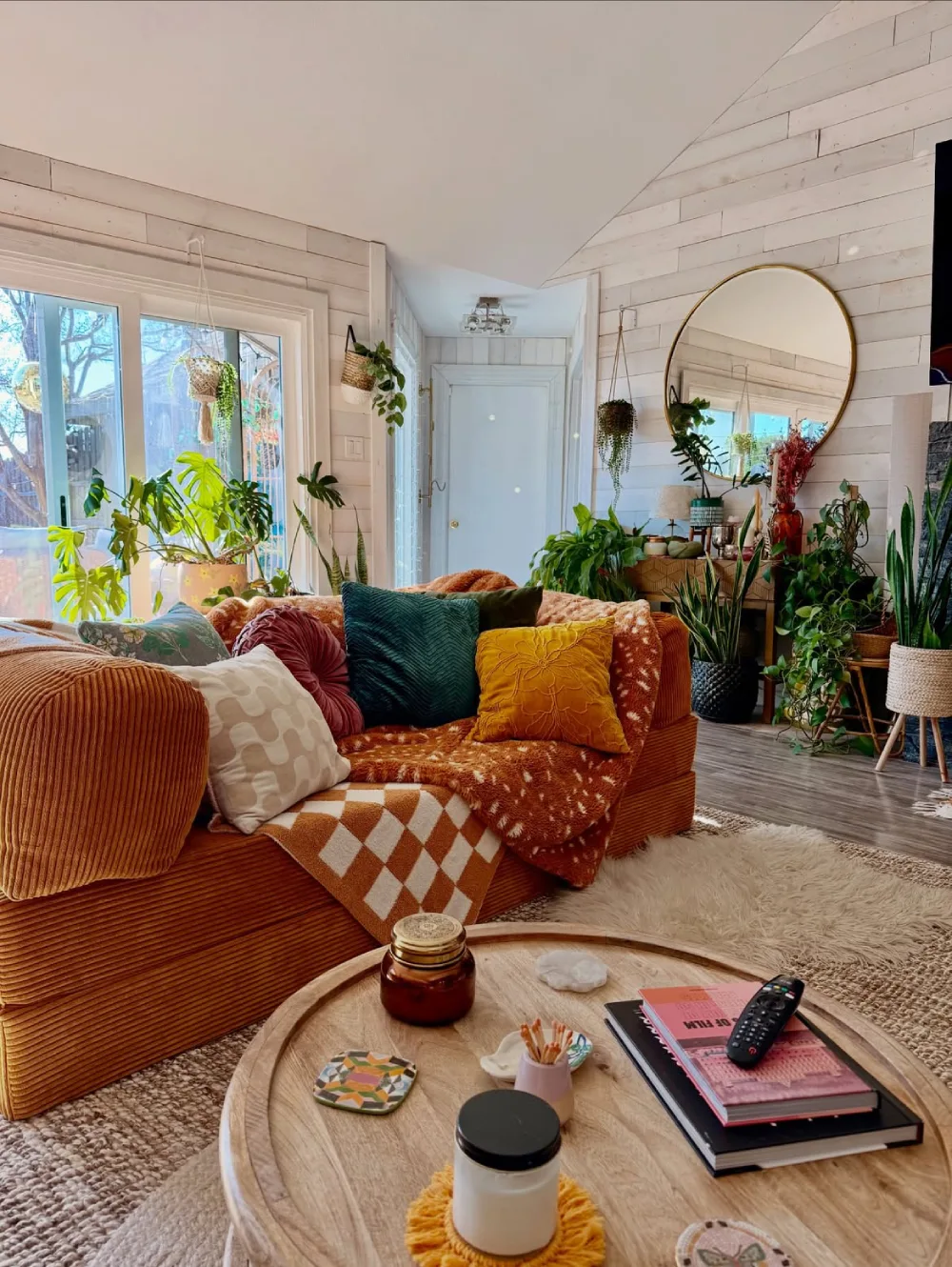 Cozy living room filled with houseplants, colorful pillows, and warm textures