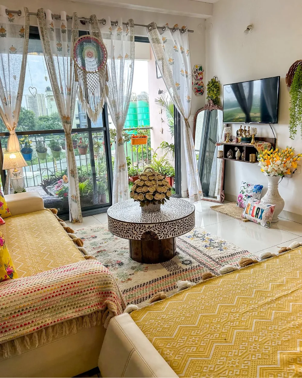 Colorful cream living room with patterned yellow sofas, textured throws, and a decorative round coffee table